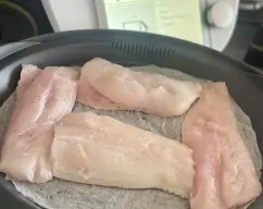 Step <p>Ponga el aceite en el vaso y caliente 5 min/120°C/vel 1. Mientras tanto, engrase el recipiente y la bandeja Varoma y coloque los lomos de merluza. Tape el Varoma y reserve.</p> illustration