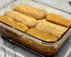 Step <p>Vierta con cuidado la mezcla en el molde caramelizado, coloque encima el resto de las magdalenas cubriéndolo todo, ya que será la base del pudin. </p> illustration