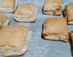 Step <p>Una vez horneados esperamos a que templen un poco para cortarlos por la mitad separando una tapa inferior y una superior (como si fuera para hacer un sandwich)y rellenamos con el queso y jamon a gusto</p> illustration